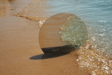 Photo of Round mirror reflecting sea on sandy beach. Space for text