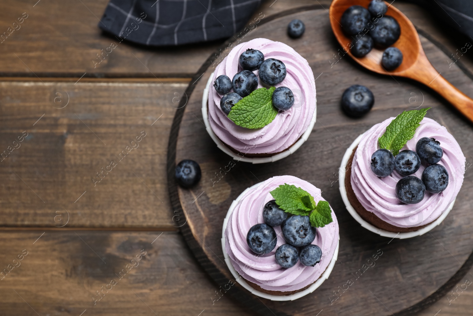 Photo of Sweet cupcakes with fresh blueberries on wooden table, flat lay. Space for text