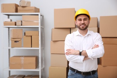 Young man near cardboard boxes at warehouse