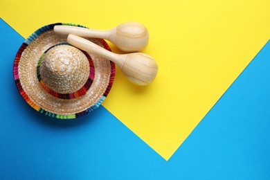 Photo of Wooden maracas and sombrero hat on colorful background, flat lay with space for text. Musical instrument
