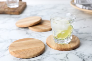 Photo of Glass of lemonade and stylish cup coasters on marble table, space for text
