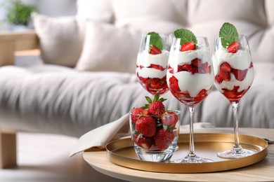Photo of Delicious strawberries with whipped cream on wooden table indoors,space for text
