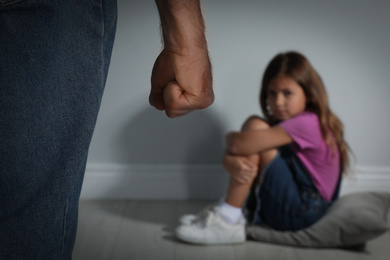 Photo of Man threatening his daughter indoors, closeup. Domestic violence concept