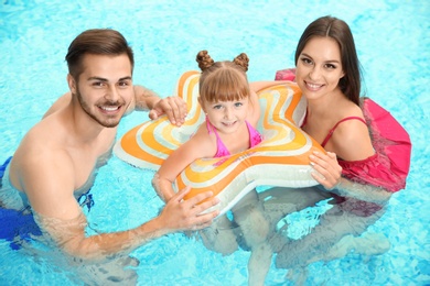 Photo of Happy family with inflatable ring in swimming pool