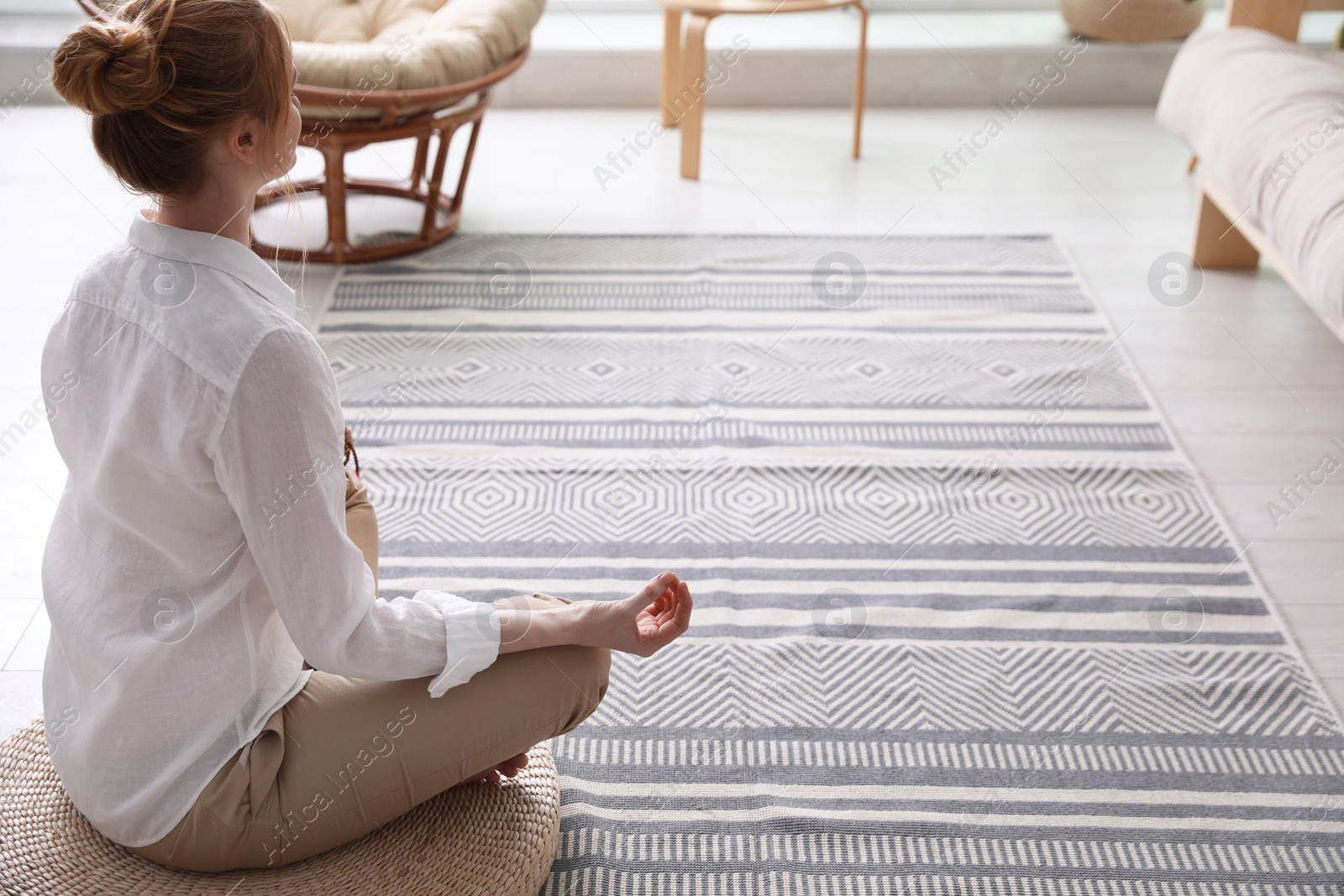 Photo of Woman meditating on wicker mat at home. Space for text