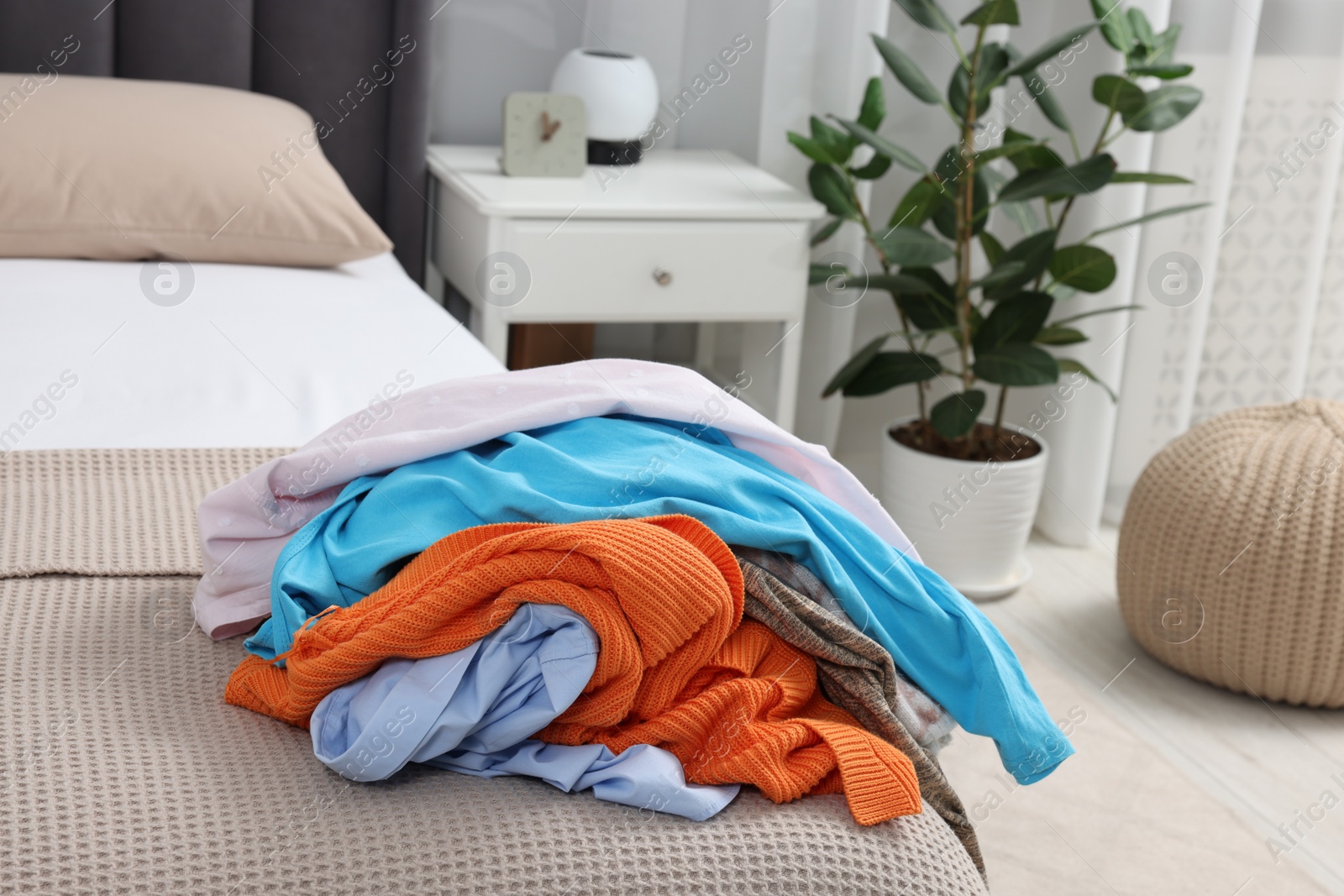 Photo of Pile of different clothes on bed at home