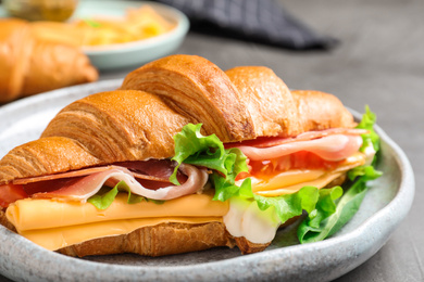 Photo of Tasty croissant sandwich with ham and cheese on grey table, closeup