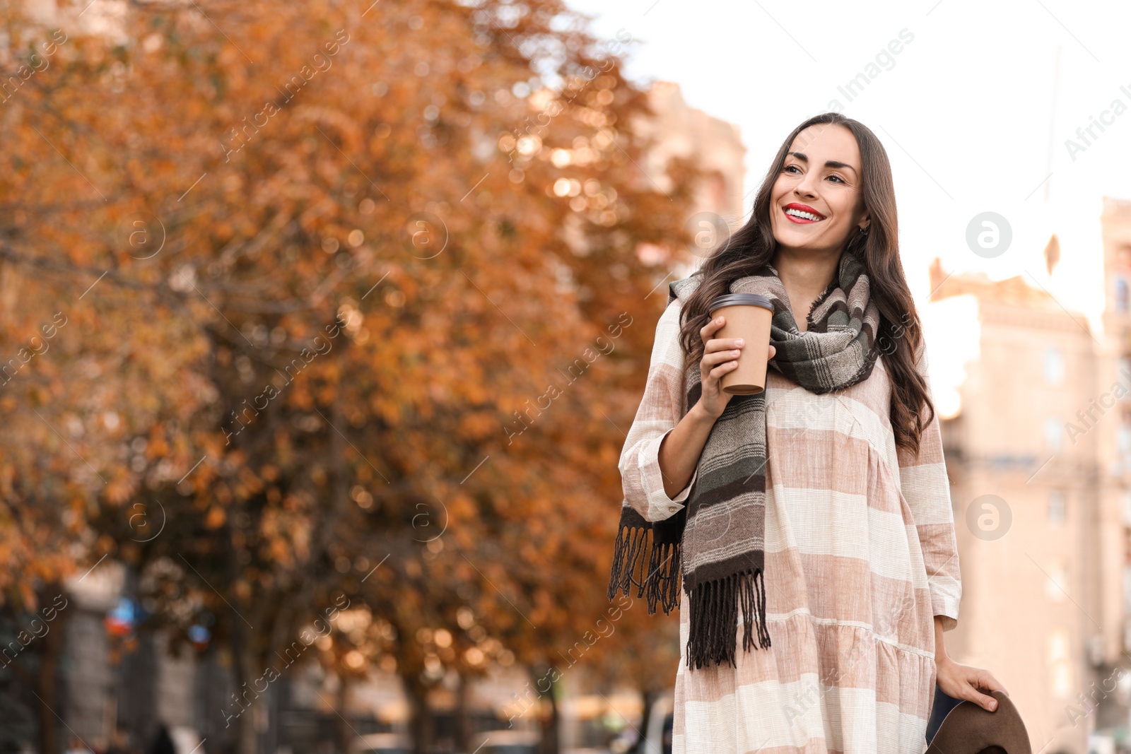 Photo of Beautiful woman with cup of coffee on city street. Autumn walk