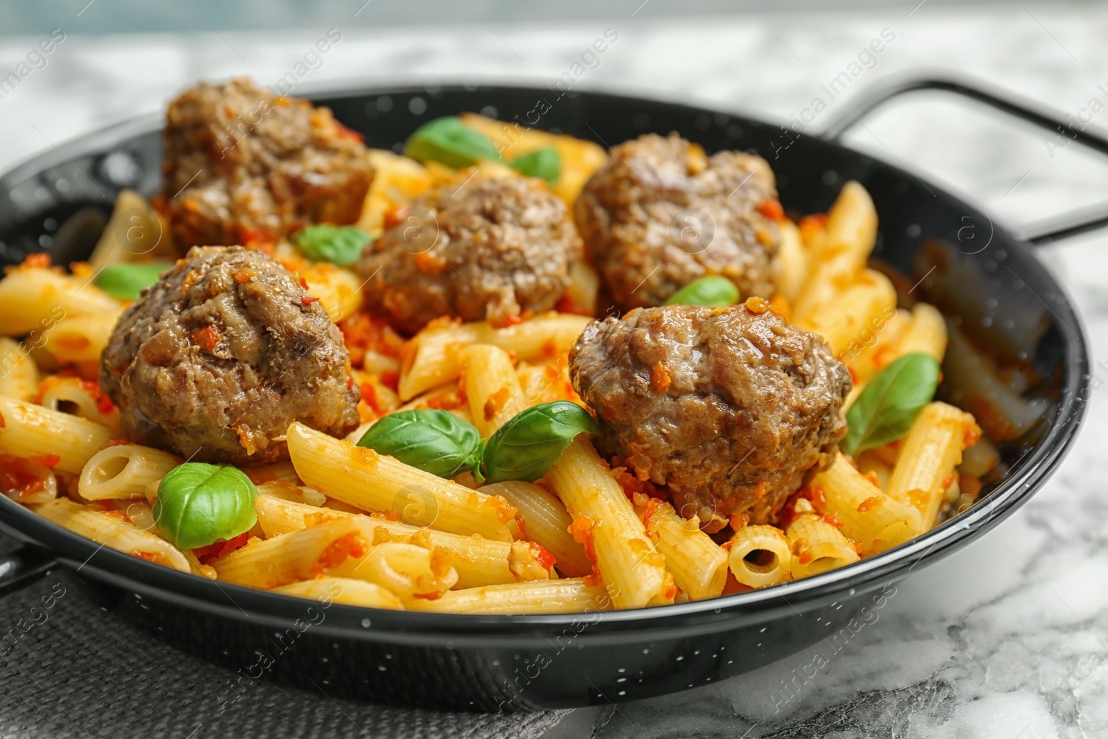 Photo of Pasta with meatballs and tomato sauce on frying pan, closeup