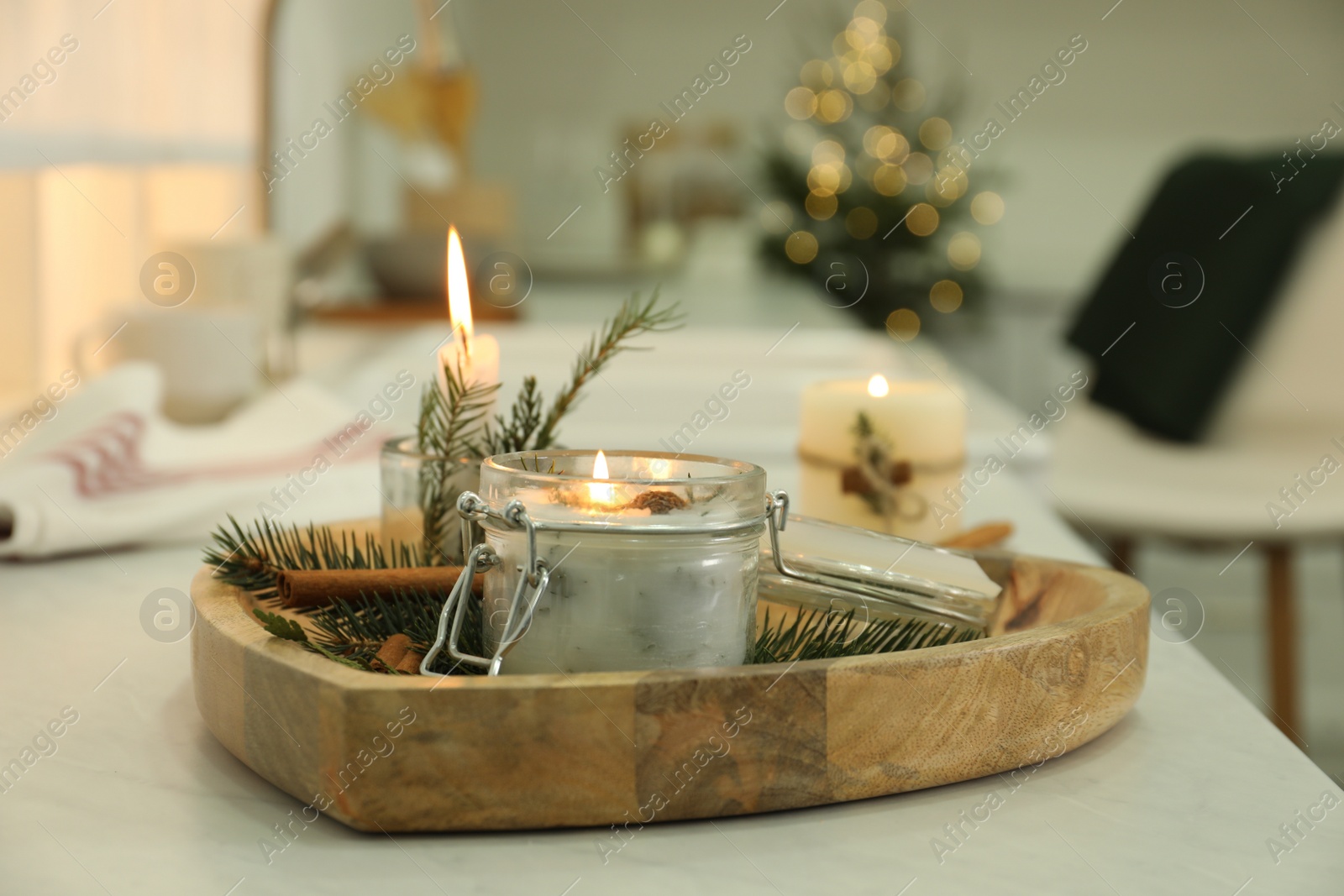 Photo of Burning scented conifer candle on white table indoors