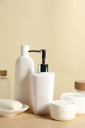 Photo of Different bath accessories on wooden table against beige background