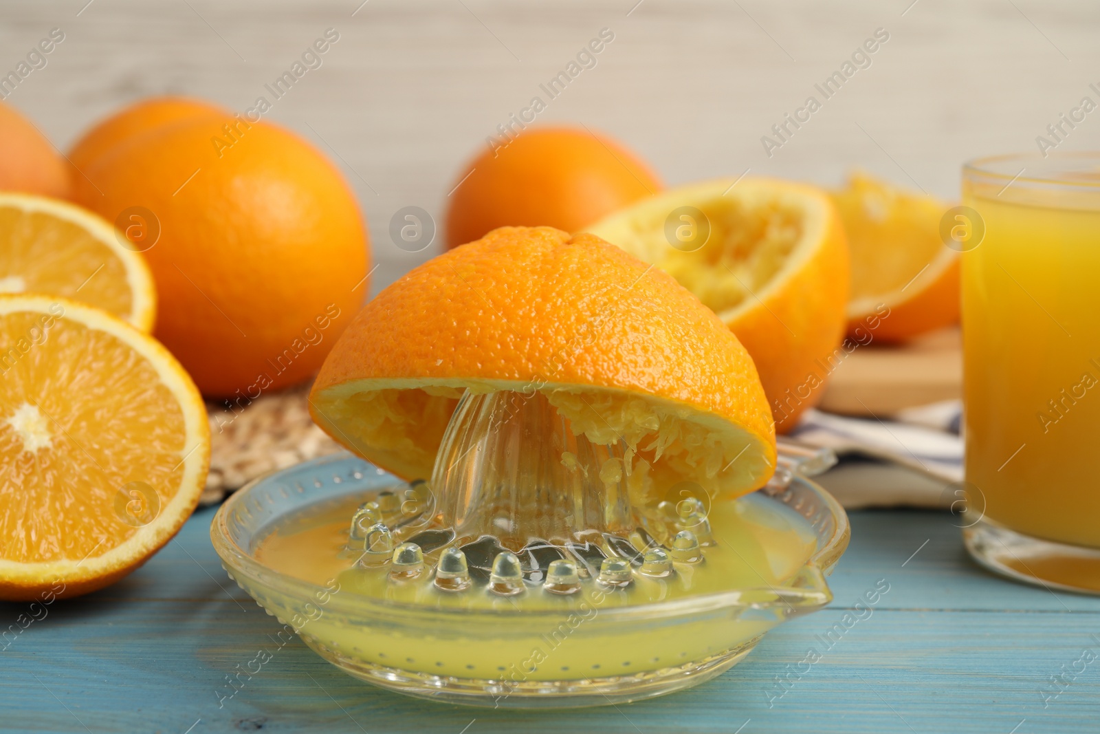 Photo of Fresh oranges and squeezer on blue wooden table, closeup