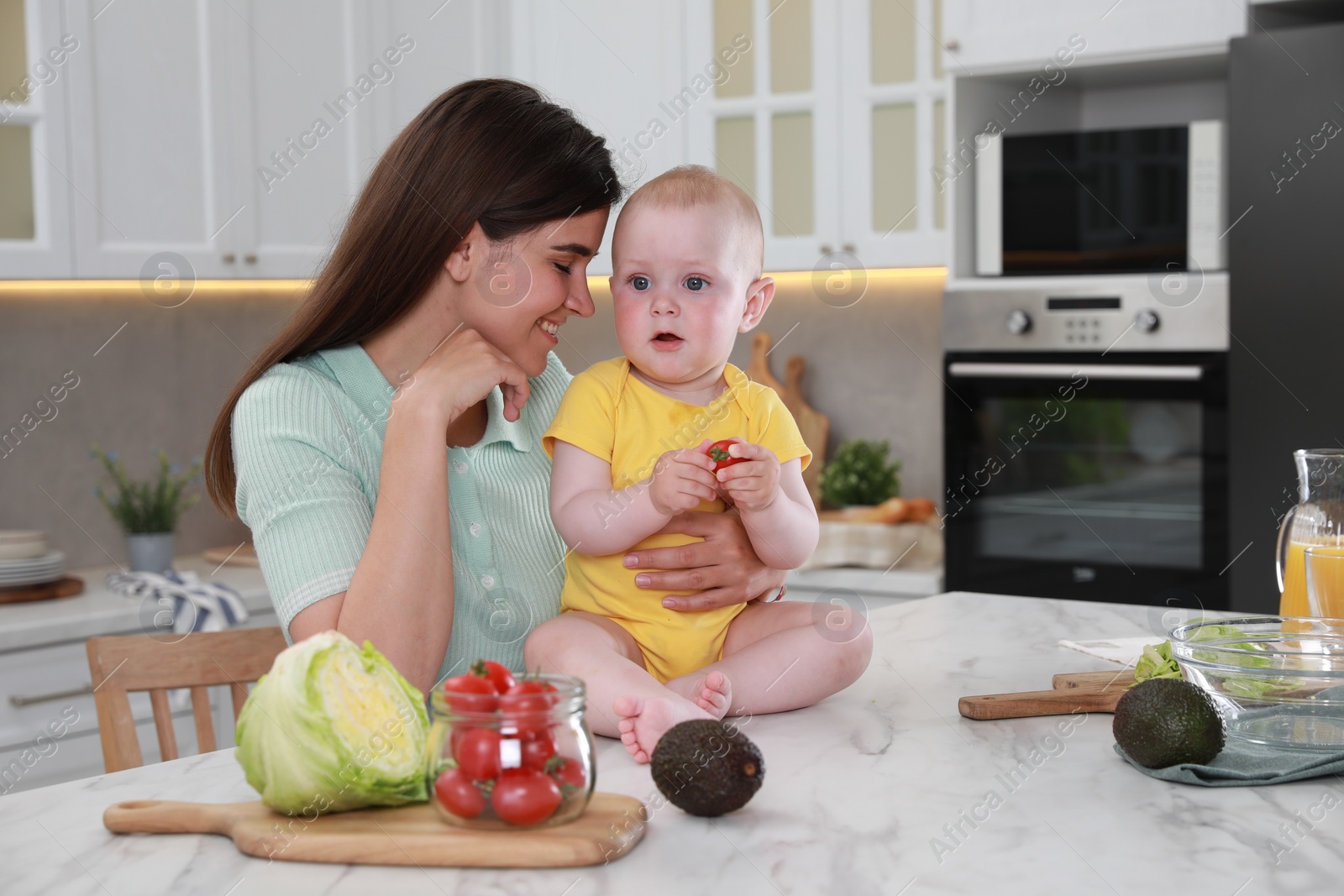 Photo of Happy young woman and her cute little baby cooking together in kitchen