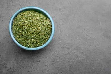 Bowl with dried thyme on grey table, top view. Space for text