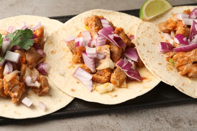 Photo of Delicious tacos with vegetables, meat and lime on grey textured table, closeup