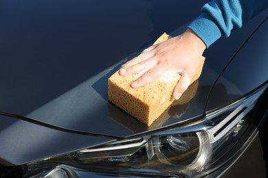 Photo of Man washing car hood with sponge, closeup