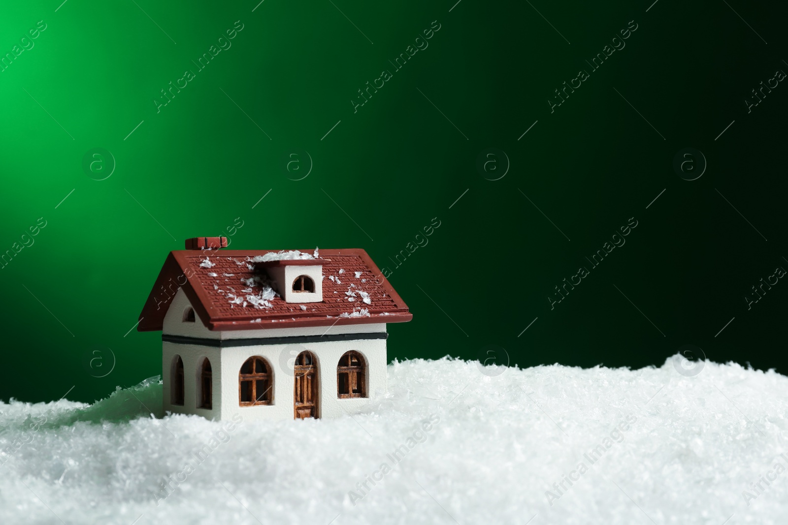 Photo of Decorative house in snowdrift on color background, space for text. Winter weather