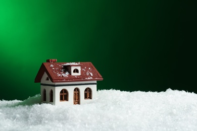 Decorative house in snowdrift on color background, space for text. Winter weather