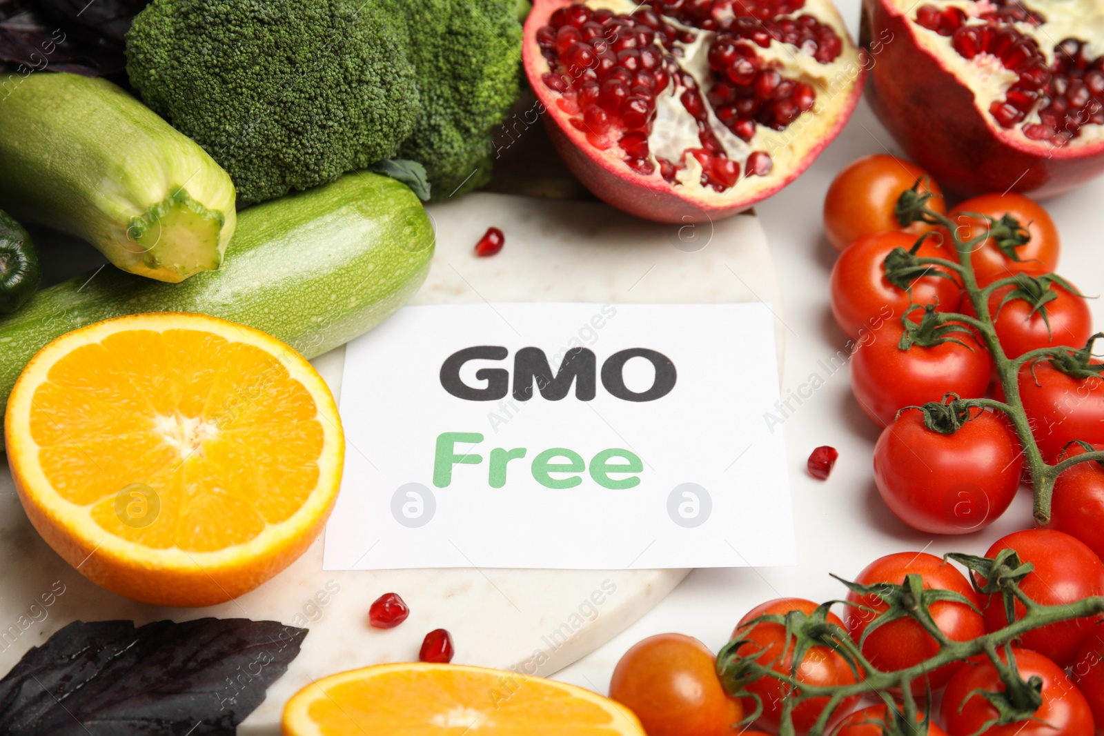 Photo of Tasty fresh GMO free products and paper card on white table