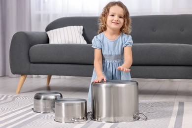 Photo of Little girl pretending to play drums on pots at home