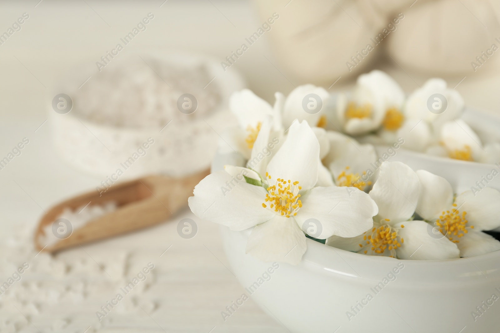 Photo of Mortar with beautiful jasmine flowers and pestle on white table, closeup. Space for text