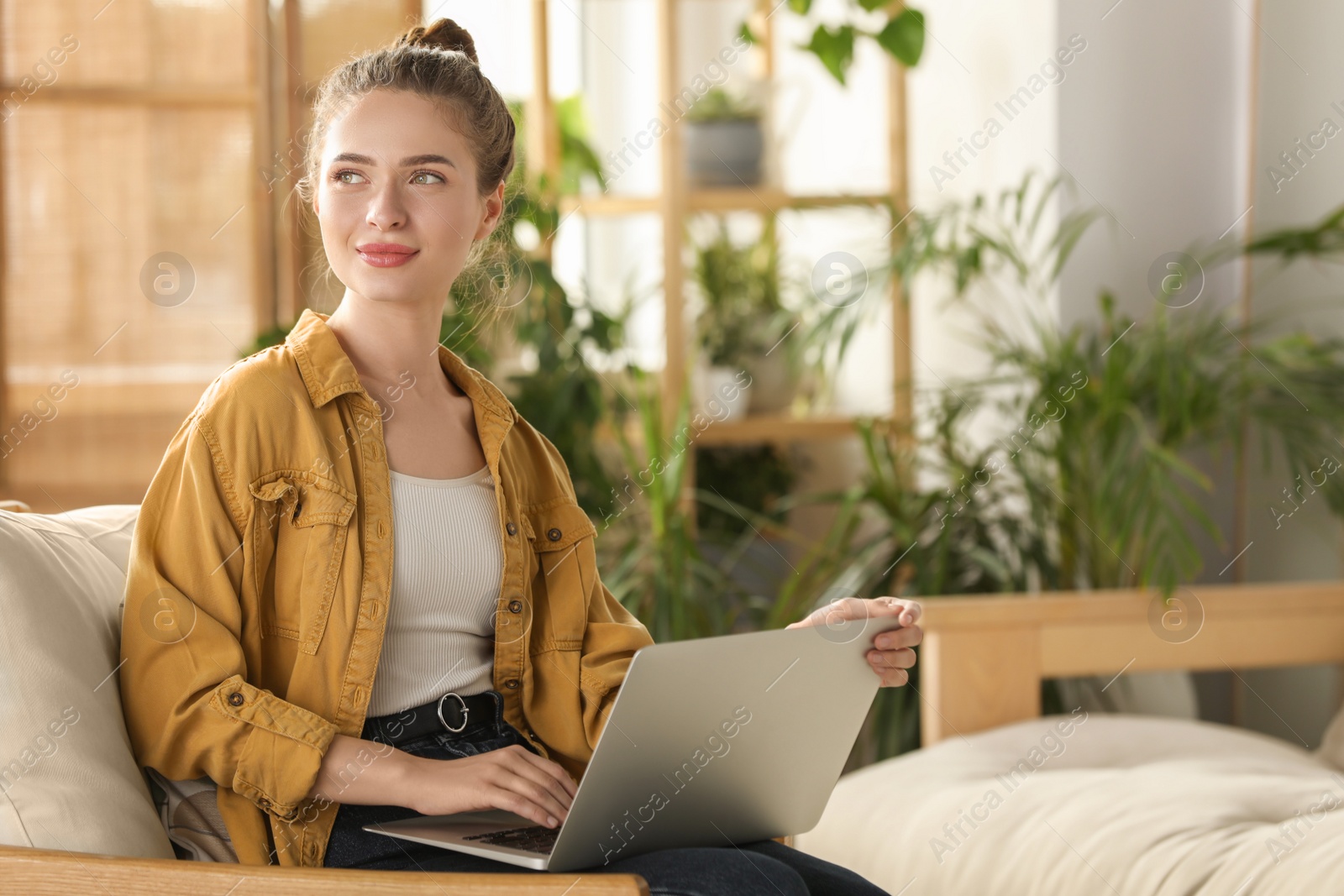 Photo of Happy young woman with laptop on armchair at home