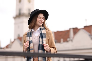 Photo of Beautiful woman in warm scarf and hat outdoors, space for text