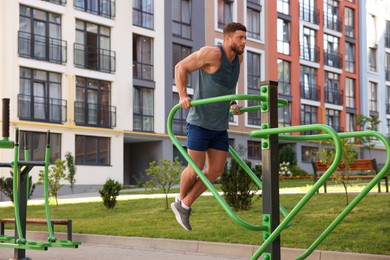 Photo of Man training on parallel bars at outdoor gym