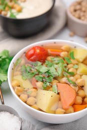 Tasty chickpea soup in bowls on white tiled table