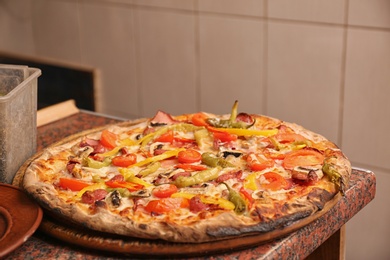 Photo of Wooden board with delicious pizza on table in restaurant. Fresh from oven