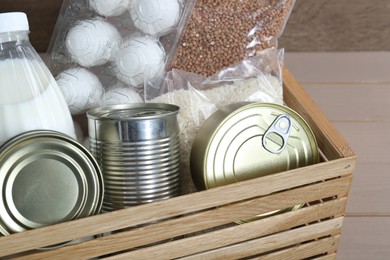 Photo of Donation box with food products on wooden table, closeup