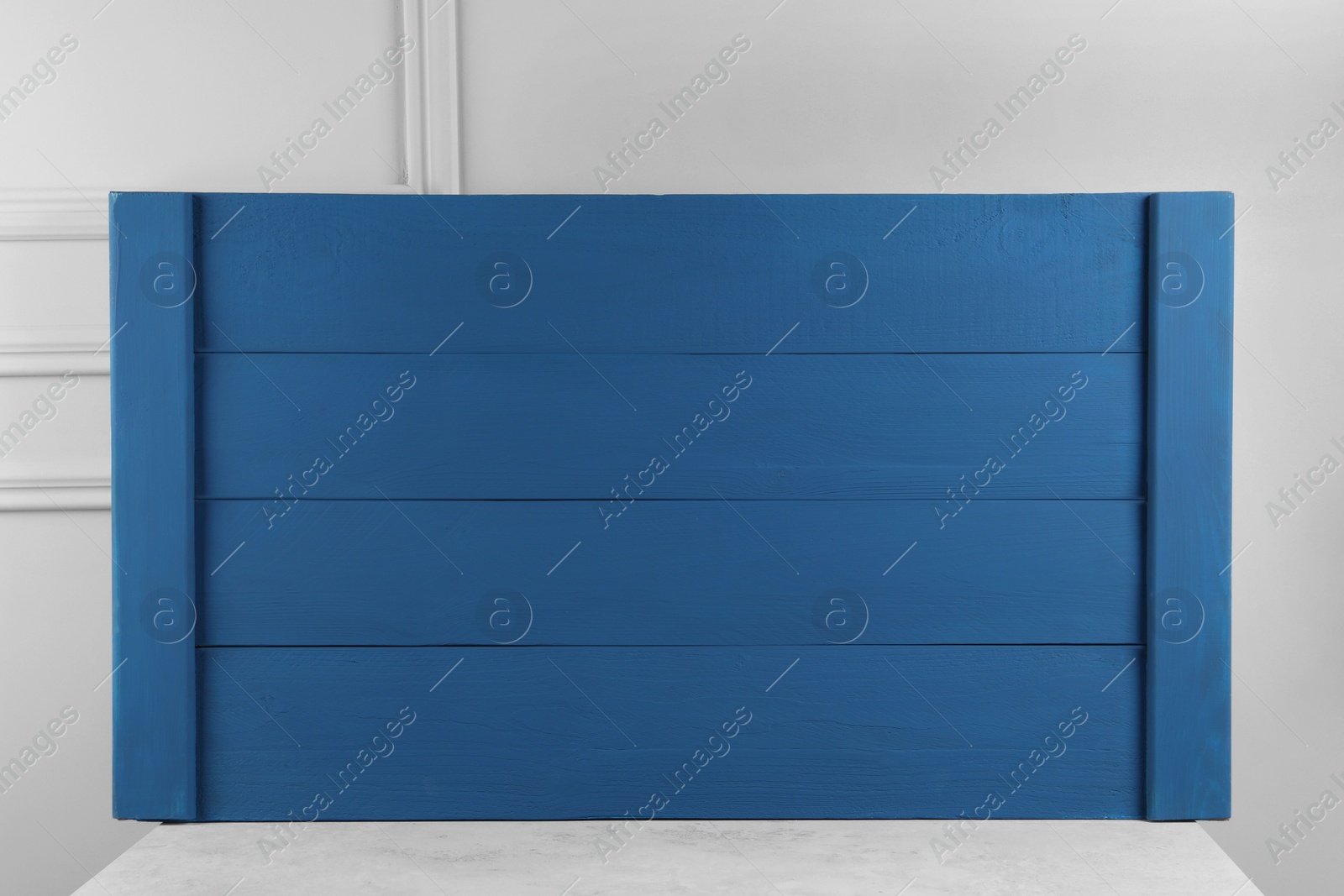 Photo of Texture of dark blue wooden board on table near light grey wall