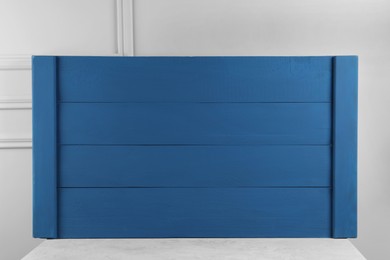Texture of dark blue wooden board on table near light grey wall