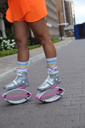 Sporty woman doing exercises in kangoo jumping boots outdoors, closeup