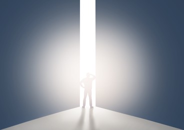 Silhouette of man standing in front of light hole, back view