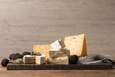 Different types of cheese and fresh truffles on wooden table