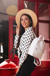 Photo of Beautiful young woman with stylish backpack and hat outdoors