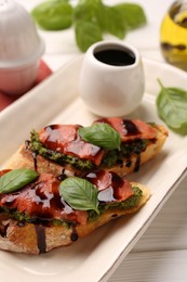 Photo of Delicious bruschettas with balsamic vinegar and toppings on white wooden table