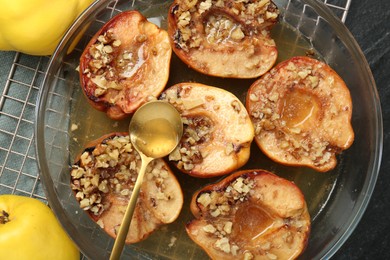 Photo of Tasty baked quinces with walnuts and honey in bowl on table, flat lay