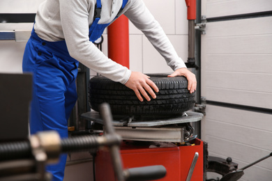 Photo of Mechanic working with tire fitting machine at car service, closeup