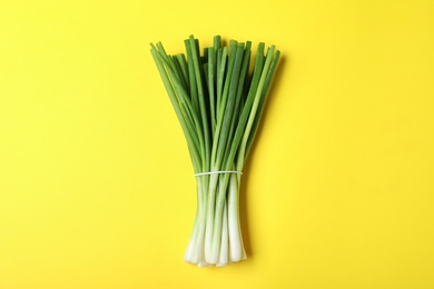 Photo of Bunch of fresh green onion on yellow background