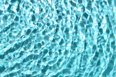 Rippled surface of clear water on light blue background, closeup