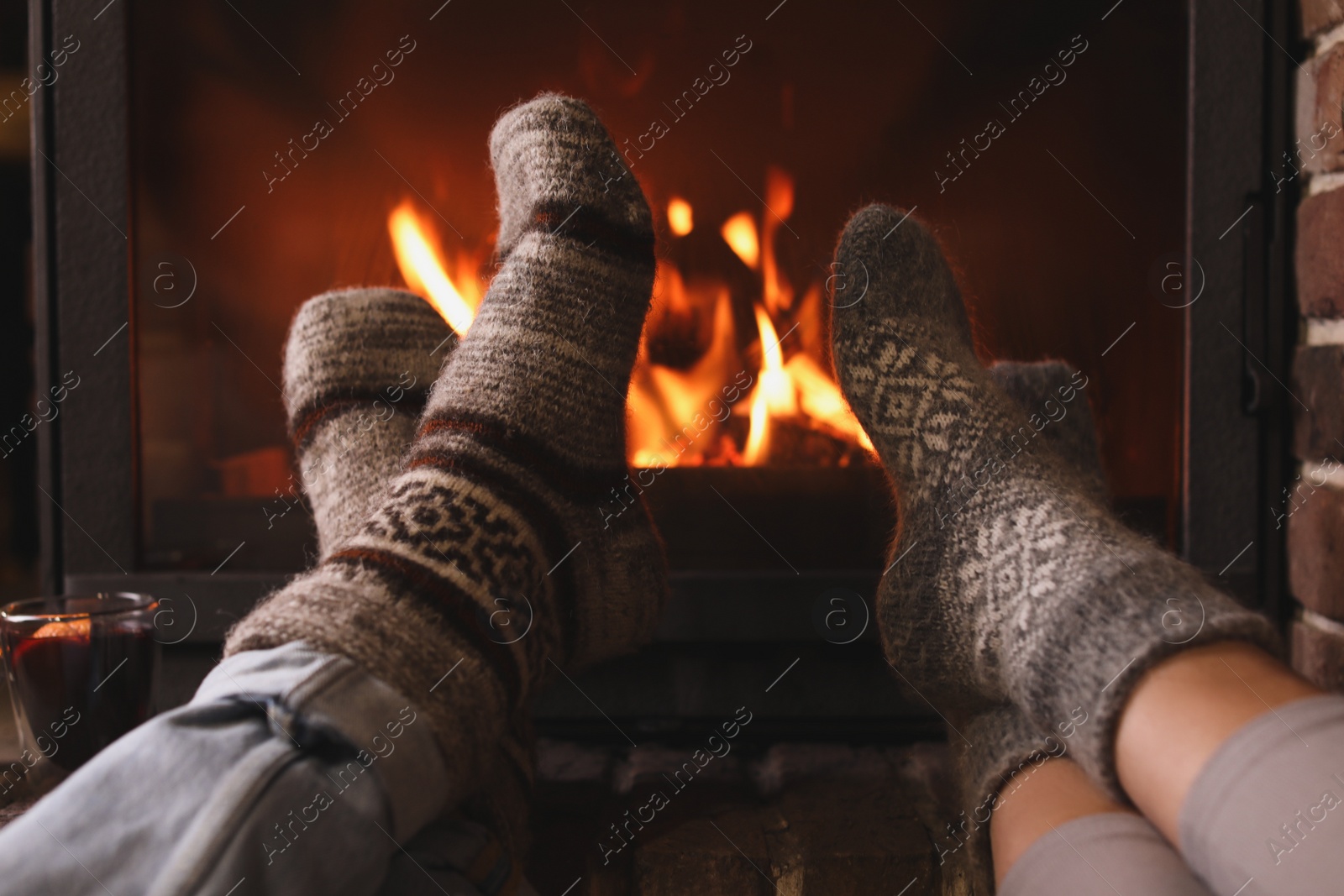 Photo of Couple resting near fireplace indoors, closeup. Winter vacation