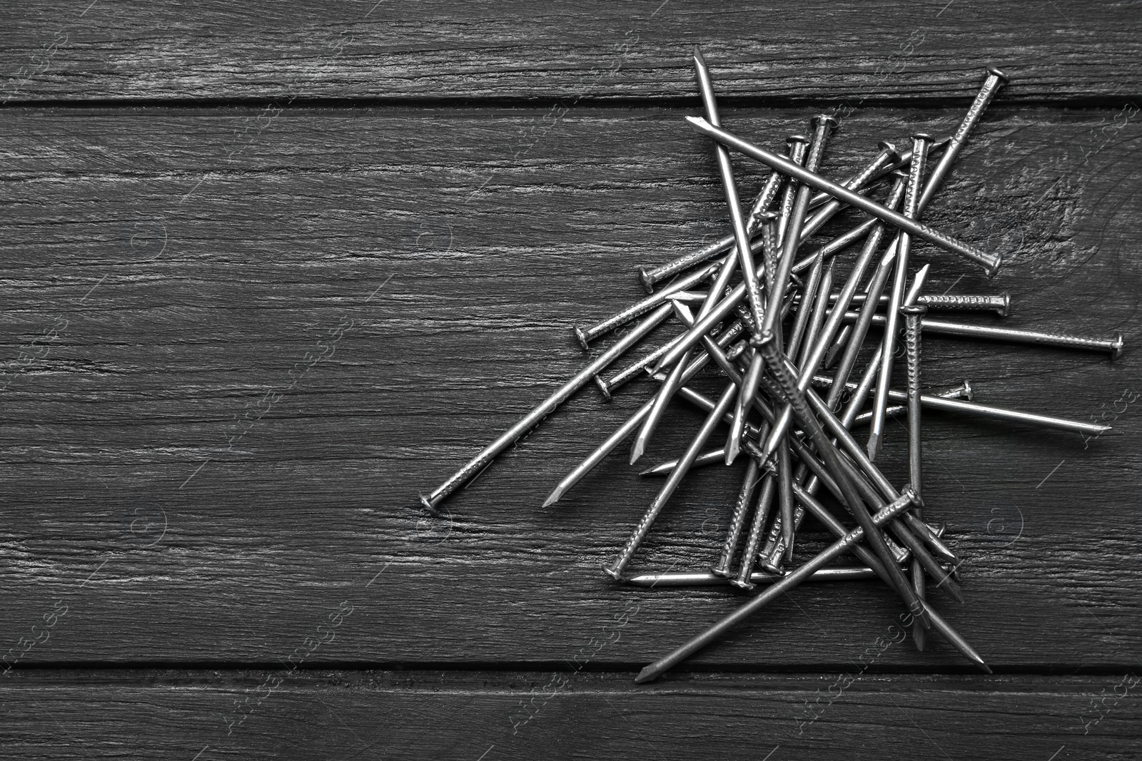 Photo of Pile of metal nails on grey wooden background, flat lay. Space for text