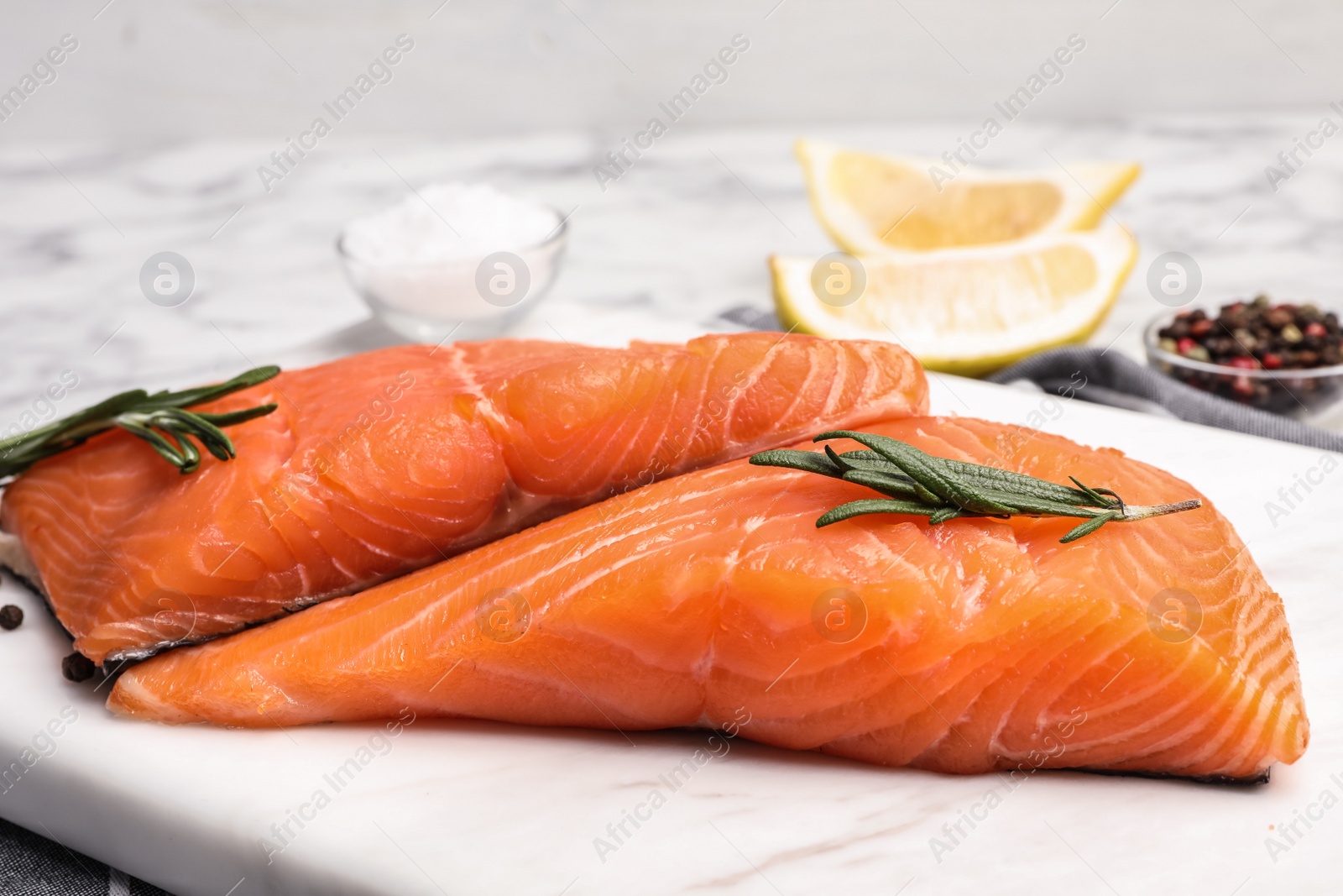 Photo of Marble board with tasty salmon fillet on table, closeup