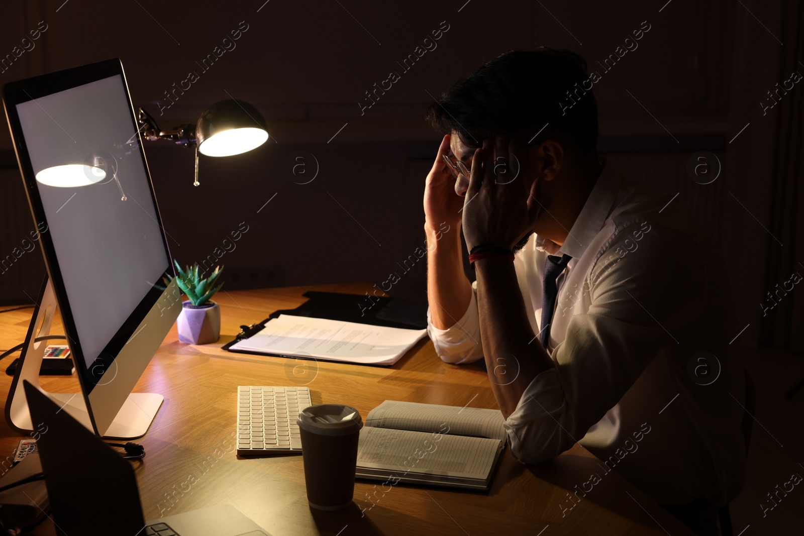 Photo of Tired young man working late in office