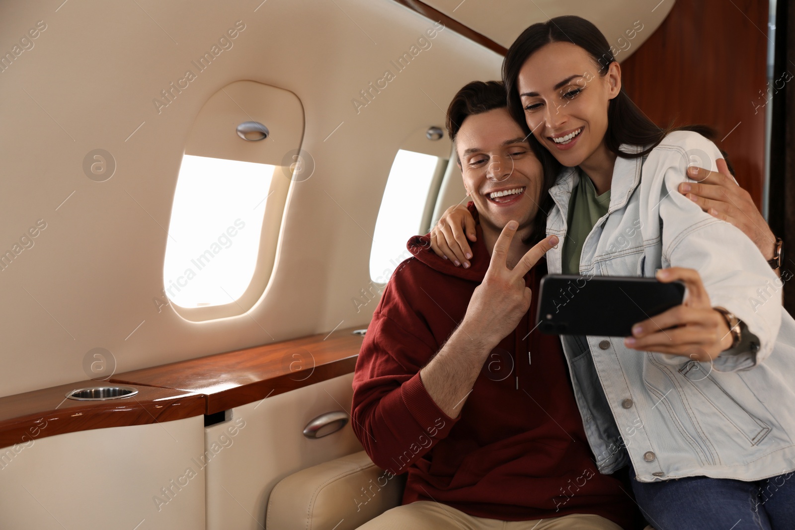 Photo of Lovely young couple taking selfie in airplane during flight