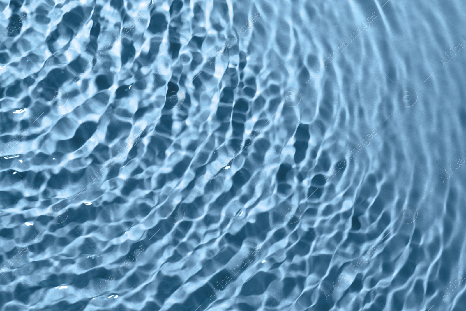 Image of Rippled surface of clear water on light blue background, closeup