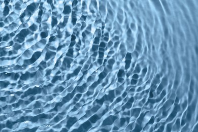 Rippled surface of clear water on light blue background, closeup