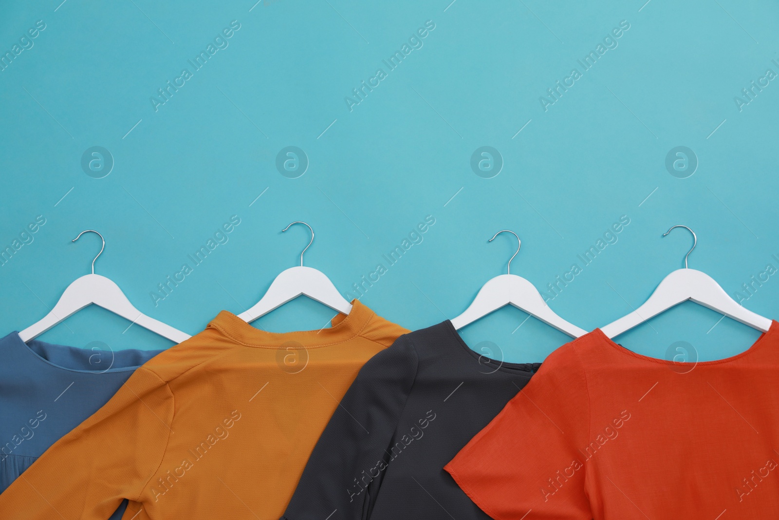 Photo of Collection of women's garments on light blue background, flat lay with space for text. Clothes rent concept